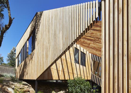 a wooden building with a fence and a tree