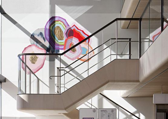 a staircase with glass railings and a mural on the wall