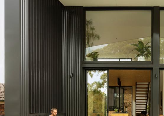 a man and woman sitting on a bench outside a house