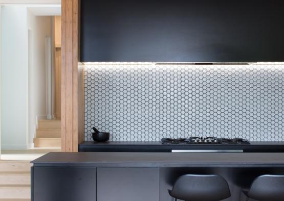 a black counter top with stools in a room with stairs