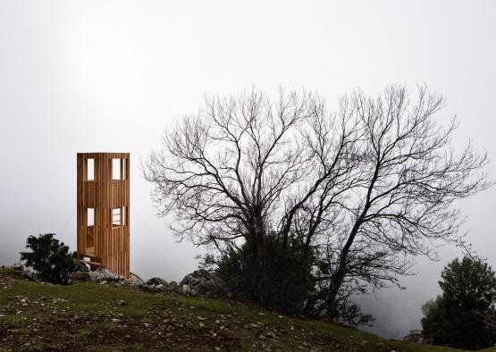 a wooden structure on a hill with trees in the background