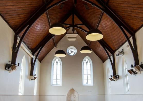 a room with a wood floor and ceiling with lights