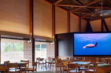 a room with tables and chairs and a large screen