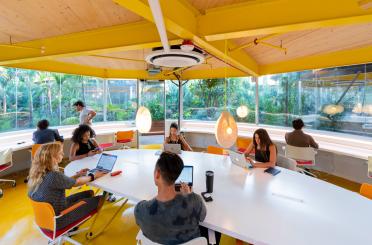 a group of people sitting at tables with laptops