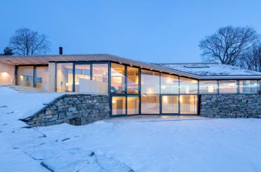 a house with a large glass wall and a stone wall