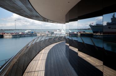 a circular building with a view of a harbor and ships