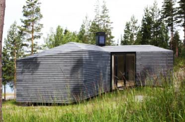 a small gray building in tall grass