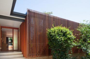 a house with a wood wall and a tree